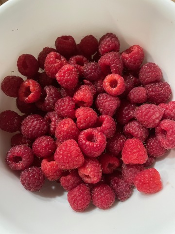 two cups of raspberries in a white bowl
